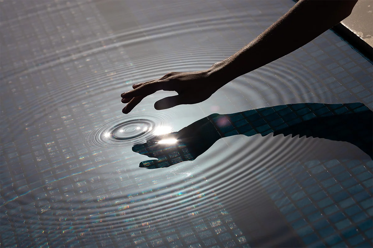 Hand touching the water in a pool Hand touching the water in a pool